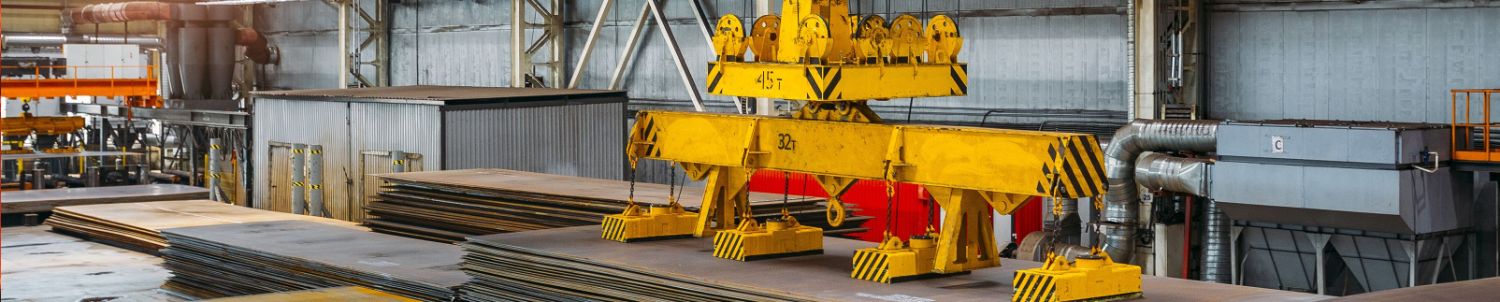 Overhead crane with electromagnetic beam grippers lifting steel sheets